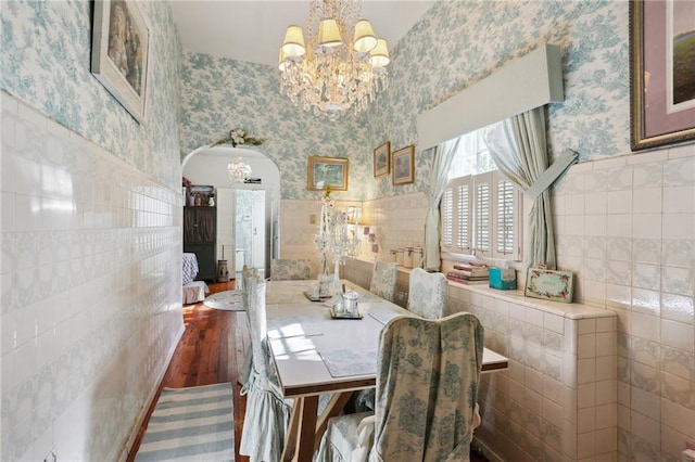 dining room with tile walls, a chandelier, and dark wood-type flooring