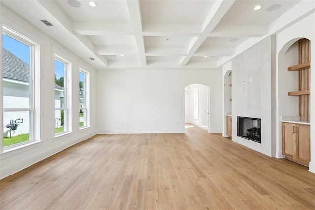 unfurnished living room featuring coffered ceiling, beamed ceiling, light hardwood / wood-style floors, and a large fireplace