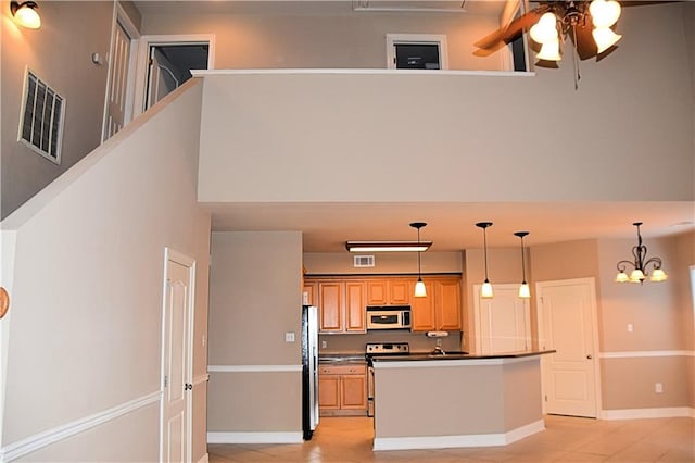 kitchen with dark countertops, appliances with stainless steel finishes, visible vents, and ceiling fan with notable chandelier