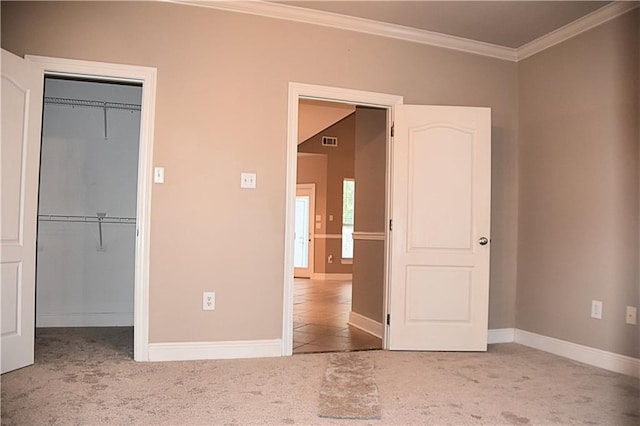 unfurnished bedroom with carpet floors, ornamental molding, and a closet