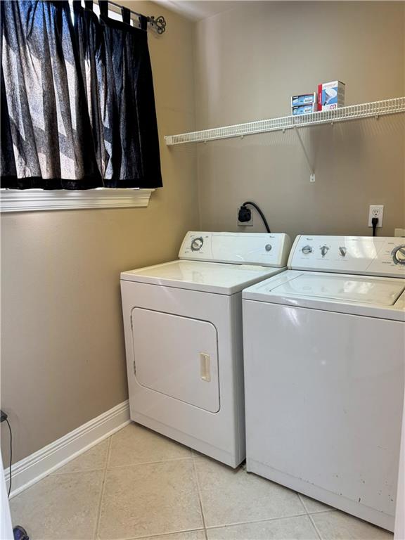 laundry room with separate washer and dryer, laundry area, baseboards, and light tile patterned floors