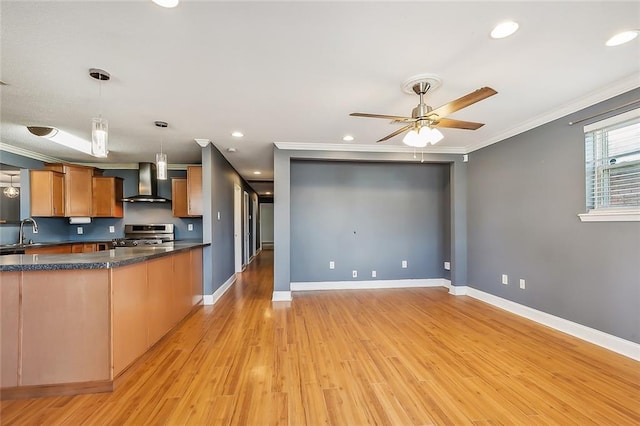 kitchen featuring pendant lighting, ornamental molding, wall chimney exhaust hood, light hardwood / wood-style flooring, and stainless steel range oven