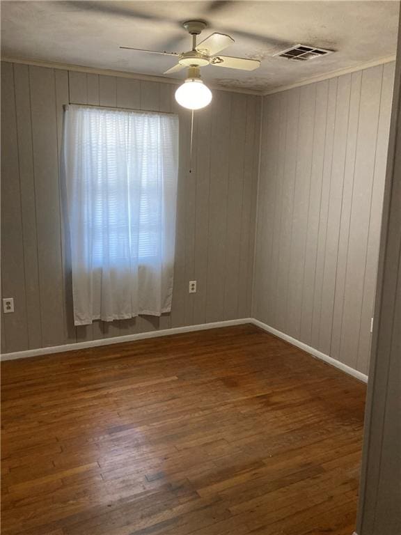 empty room featuring wooden walls, dark wood-type flooring, and ceiling fan