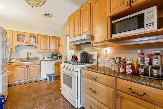 kitchen with dark stone countertops, white appliances, and sink