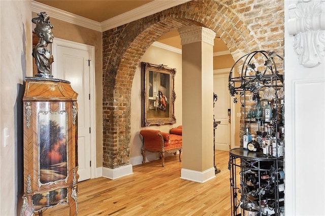 wine area with ornate columns, brick wall, light wood-type flooring, and ornamental molding