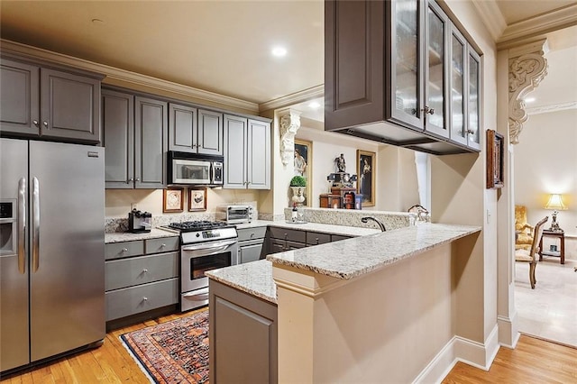 kitchen with light hardwood / wood-style floors, light stone counters, kitchen peninsula, gray cabinets, and stainless steel appliances