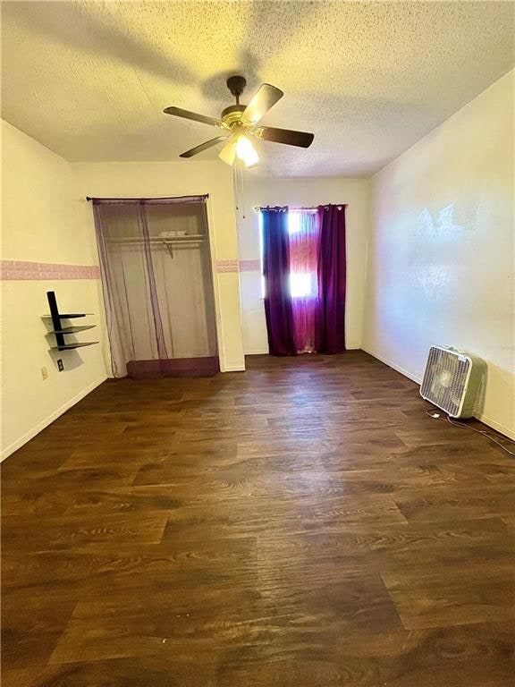 unfurnished bedroom featuring ceiling fan, a textured ceiling, a closet, and dark hardwood / wood-style flooring