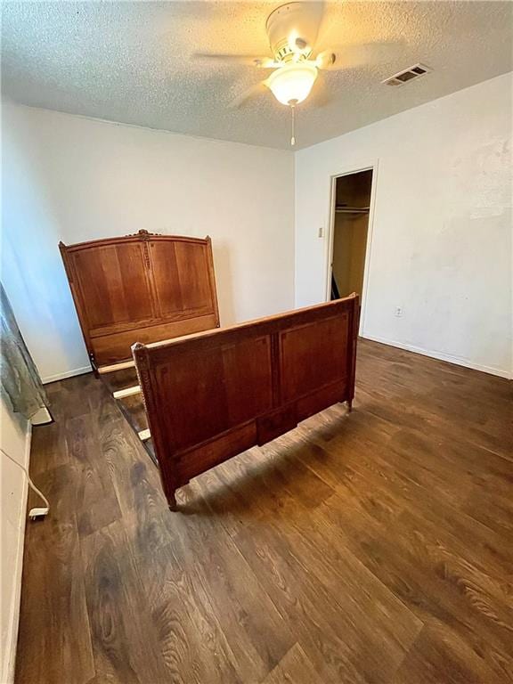 bedroom featuring a closet, ceiling fan, dark wood-type flooring, and a textured ceiling