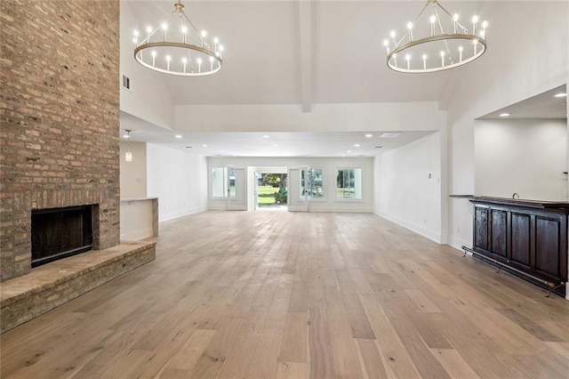 unfurnished living room with light hardwood / wood-style floors, high vaulted ceiling, beamed ceiling, and a large fireplace