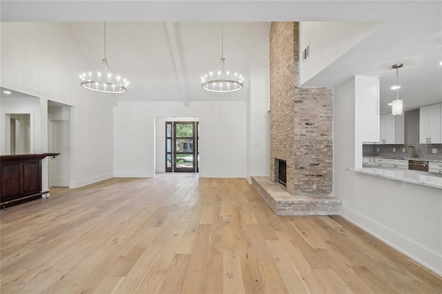 unfurnished living room featuring light hardwood / wood-style floors, beam ceiling, and high vaulted ceiling