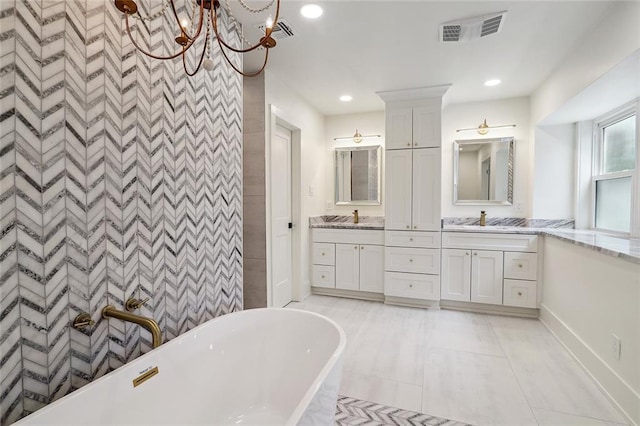 bathroom featuring vanity, tile patterned flooring, a chandelier, and a bathing tub