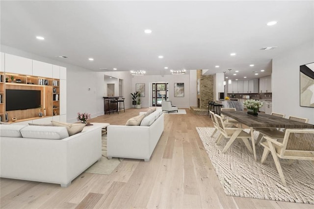 living room with an inviting chandelier and light wood-type flooring