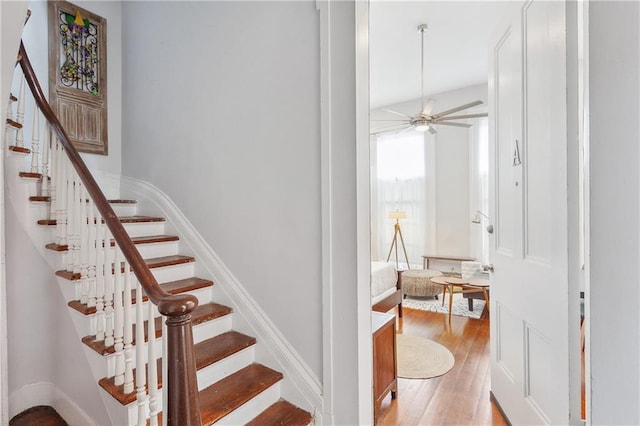 stairs with lofted ceiling, ceiling fan, and hardwood / wood-style flooring