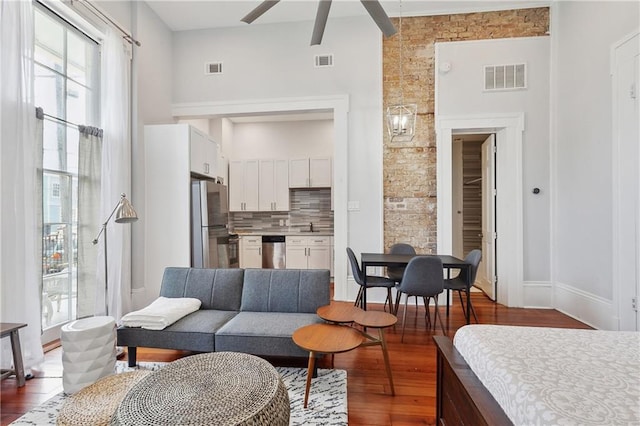 living room with ceiling fan, a towering ceiling, sink, and wood-type flooring