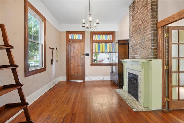 entrance foyer with wood-type flooring, a fireplace, and a chandelier