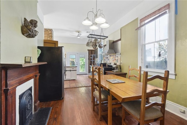 dining space with french doors, ceiling fan with notable chandelier, dark wood-type flooring, and a wealth of natural light