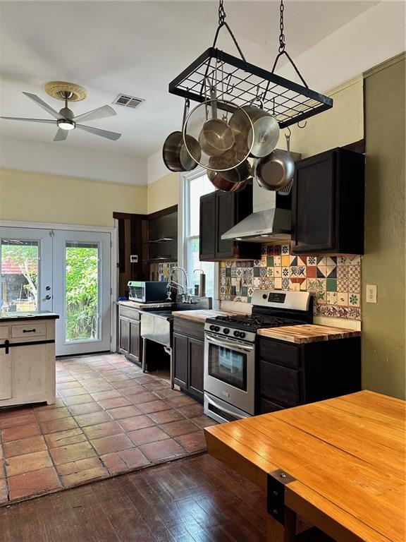 kitchen featuring appliances with stainless steel finishes, decorative backsplash, wood-type flooring, ceiling fan, and decorative light fixtures