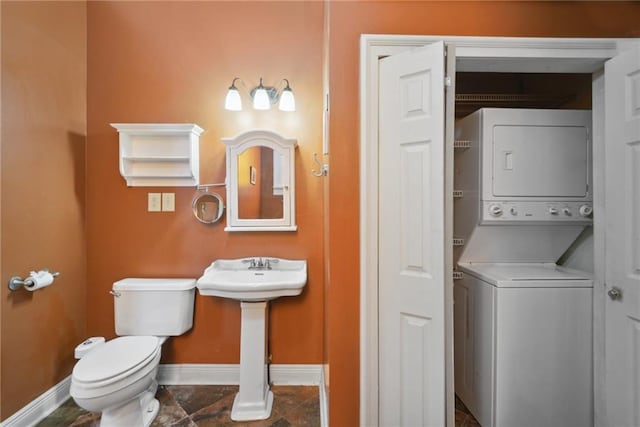 bathroom featuring toilet and stacked washer / drying machine