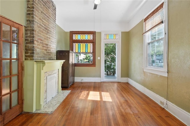 interior space with wood-type flooring, a fireplace, ceiling fan, and a wealth of natural light