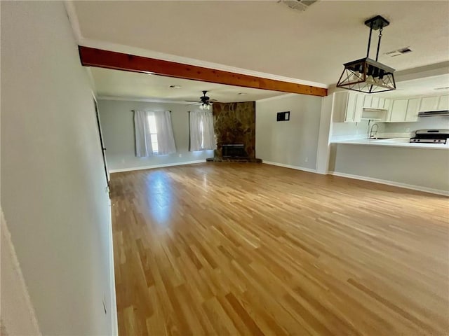 unfurnished living room featuring baseboards, visible vents, beam ceiling, and light wood finished floors
