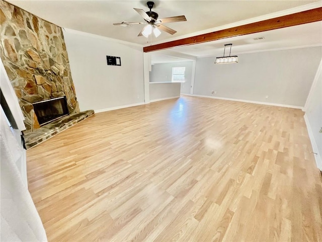 unfurnished living room featuring a stone fireplace, crown molding, baseboards, and light wood finished floors