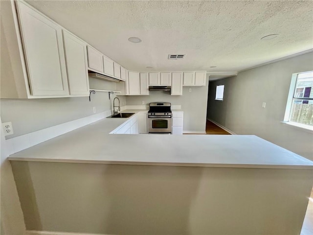 kitchen with gas stove, a textured ceiling, sink, white cabinets, and kitchen peninsula