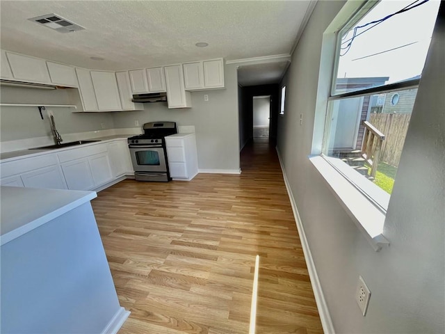 kitchen with visible vents, stainless steel range with gas stovetop, white cabinetry, a sink, and light wood-style floors