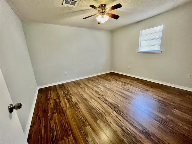 spare room with baseboards, a textured ceiling, visible vents, a ceiling fan, and wood finished floors