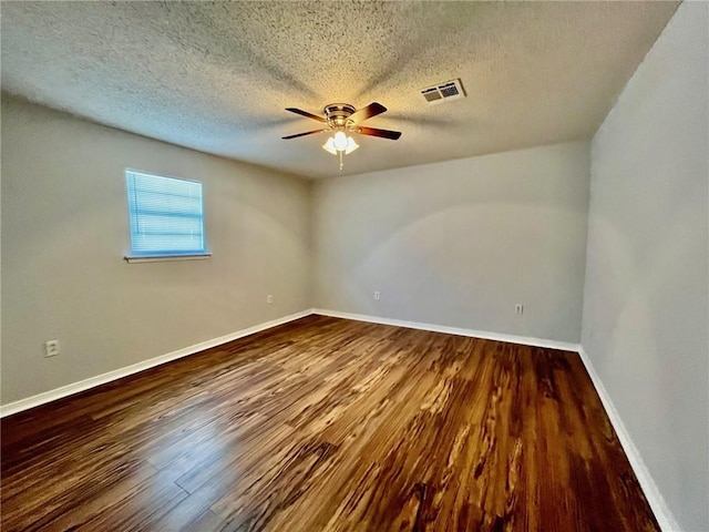 spare room with baseboards, a textured ceiling, visible vents, a ceiling fan, and wood finished floors