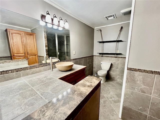 bathroom featuring tile walls, ornamental molding, visible vents, and a stall shower
