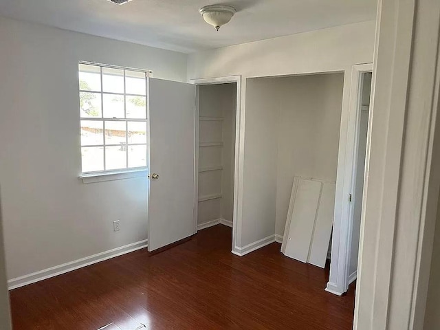 unfurnished bedroom with dark hardwood / wood-style flooring and a closet