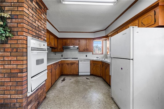 kitchen with brick wall, white appliances, a textured ceiling, crown molding, and sink