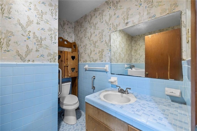 bathroom featuring tile walls, vanity, and toilet