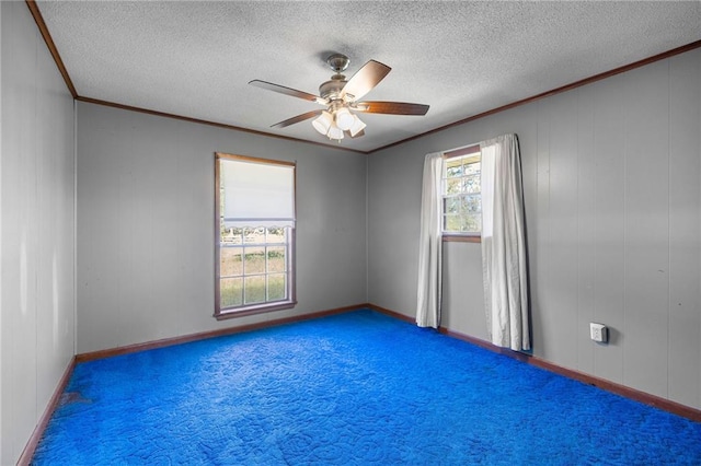 empty room featuring ceiling fan, a textured ceiling, ornamental molding, and carpet