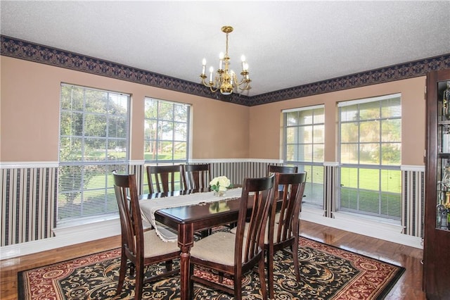 dining space featuring a notable chandelier, wood-type flooring, and a textured ceiling