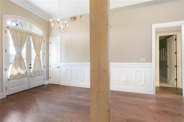 foyer entrance with ornamental molding, a notable chandelier, and dark wood-type flooring