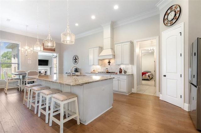 kitchen featuring white cabinets, an island with sink, light hardwood / wood-style flooring, and sink