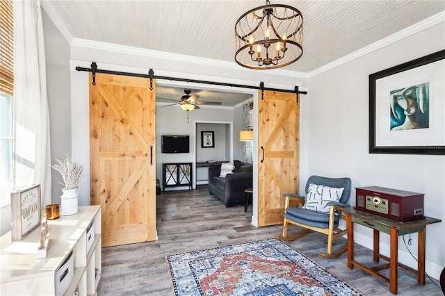 living area with a barn door, crown molding, ceiling fan with notable chandelier, and hardwood / wood-style flooring