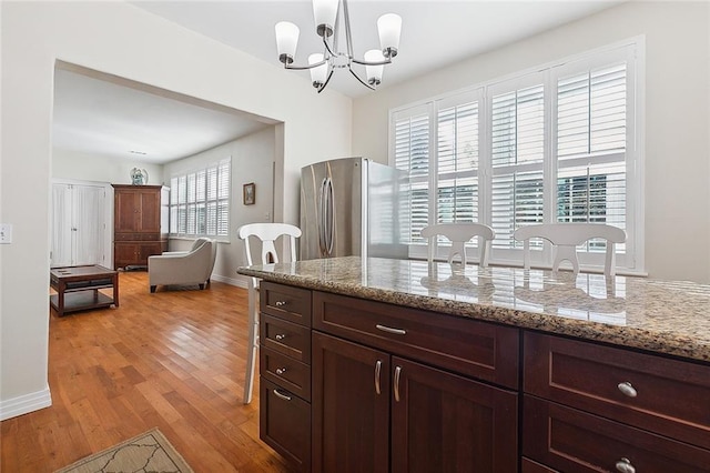 kitchen with pendant lighting, a wealth of natural light, light hardwood / wood-style flooring, and stainless steel fridge