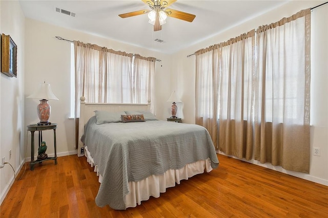 bedroom featuring ceiling fan, hardwood / wood-style floors, and multiple windows