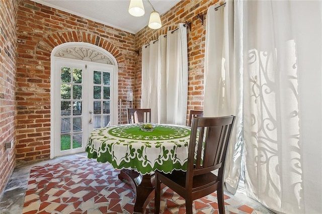 dining room featuring brick wall and french doors