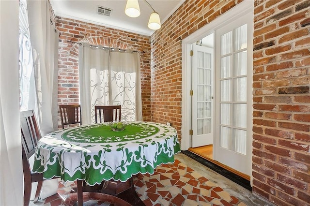 dining area featuring brick wall and plenty of natural light