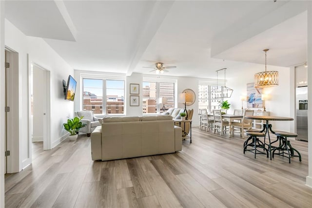 living room featuring ceiling fan with notable chandelier, light wood-type flooring, and plenty of natural light