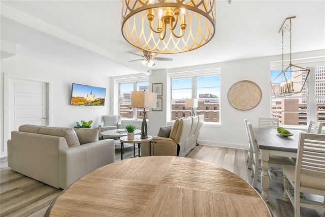 dining space featuring light wood-type flooring and ceiling fan with notable chandelier