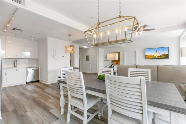 dining space with track lighting, light wood-type flooring, sink, and ceiling fan