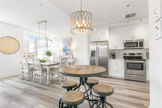 kitchen featuring rail lighting, pendant lighting, stainless steel appliances, and white cabinets