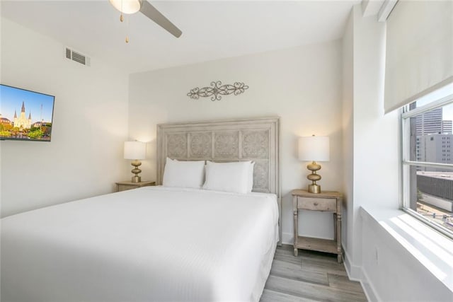 bedroom with multiple windows, ceiling fan, and light hardwood / wood-style flooring