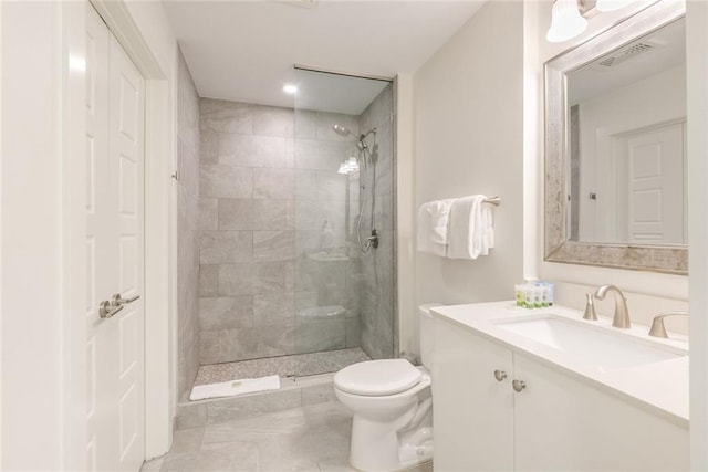 bathroom with a tile shower, vanity, and toilet