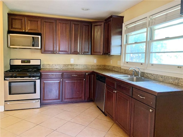 kitchen with appliances with stainless steel finishes, light tile patterned flooring, and sink