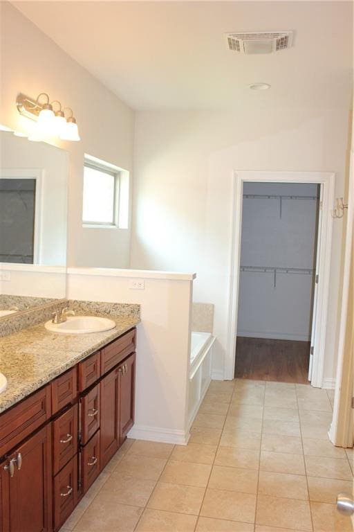 bathroom featuring tile patterned floors, a sink, double vanity, visible vents, and a walk in closet